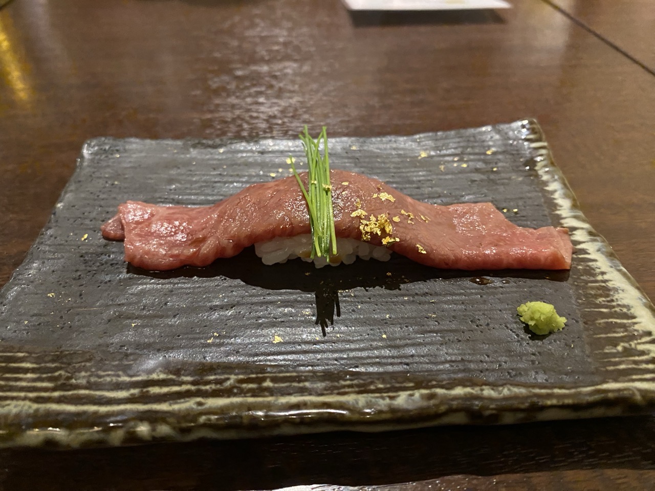 A piece of wagyu beef on a rice base, rather like sushi