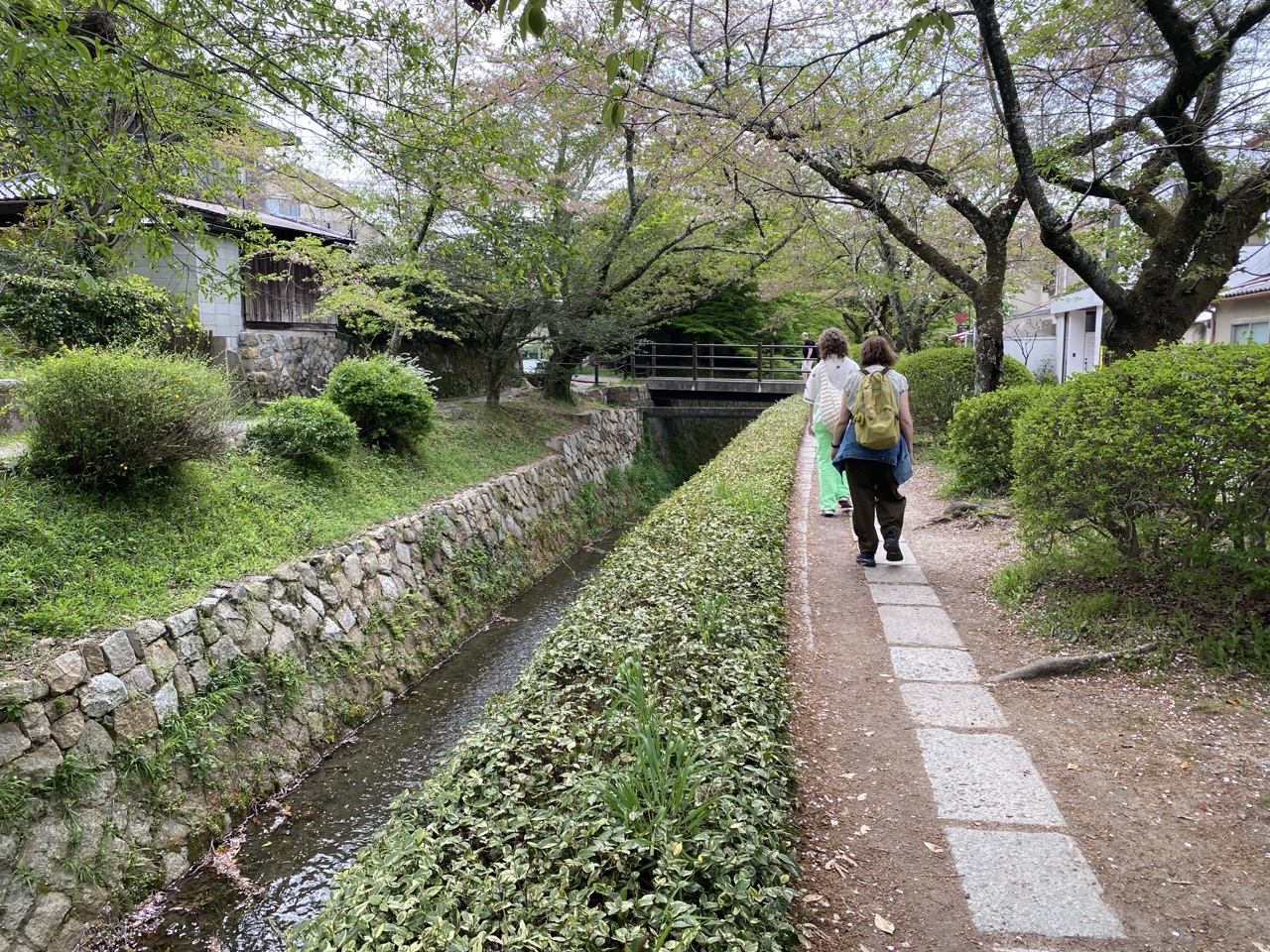 The Philosophers Walk in Kyoto. A green path by a river, with cherry blossoms
