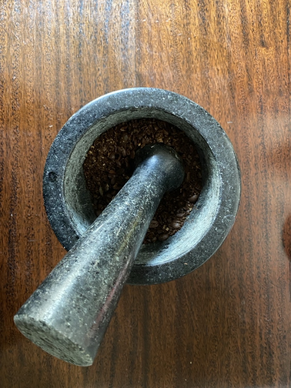 A pestle and mortar with coffee beans. You want a pretty coarse grind for cold brew or it can get overextracted (bitter).