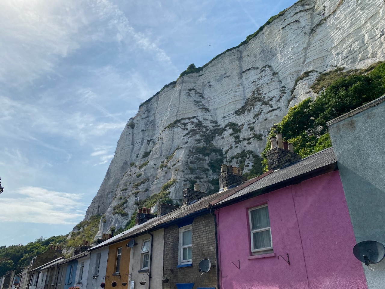 A row of colourful terraced houses, with the cliffs behind.